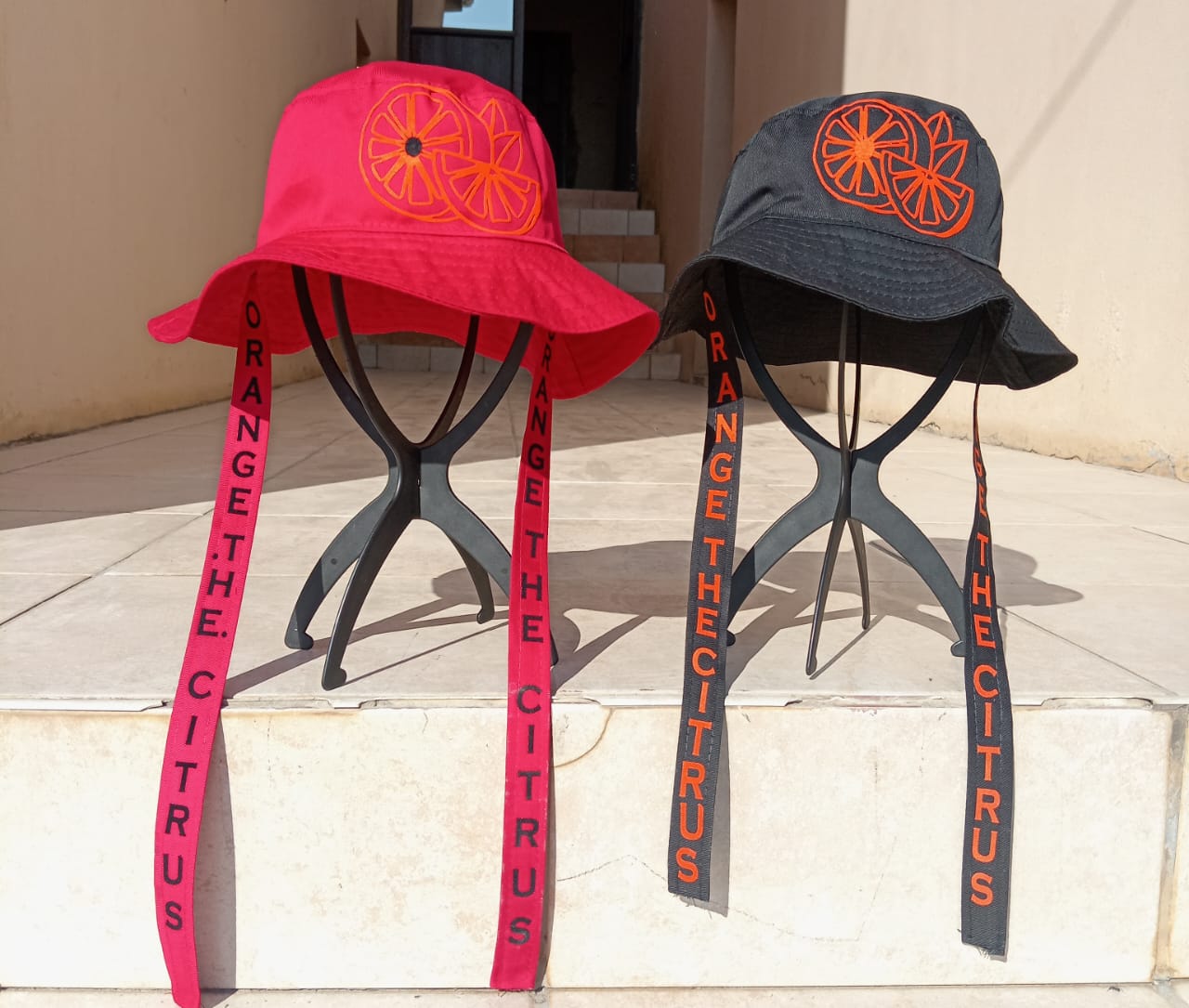 Orange The Citrus branded bucket hats in black and pink